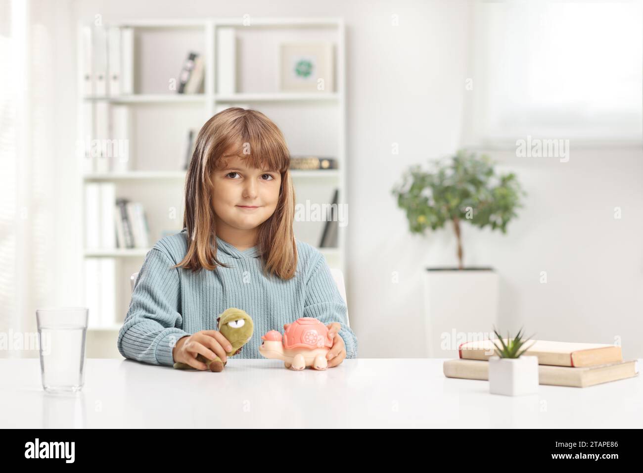 Cute little girl sitting at a table and playing with toys at home Stock Photo
