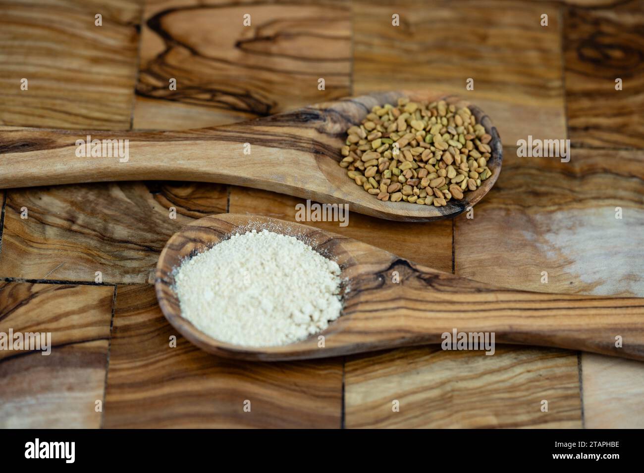 Fenugreek seeds whole or ground on olive wood Stock Photo