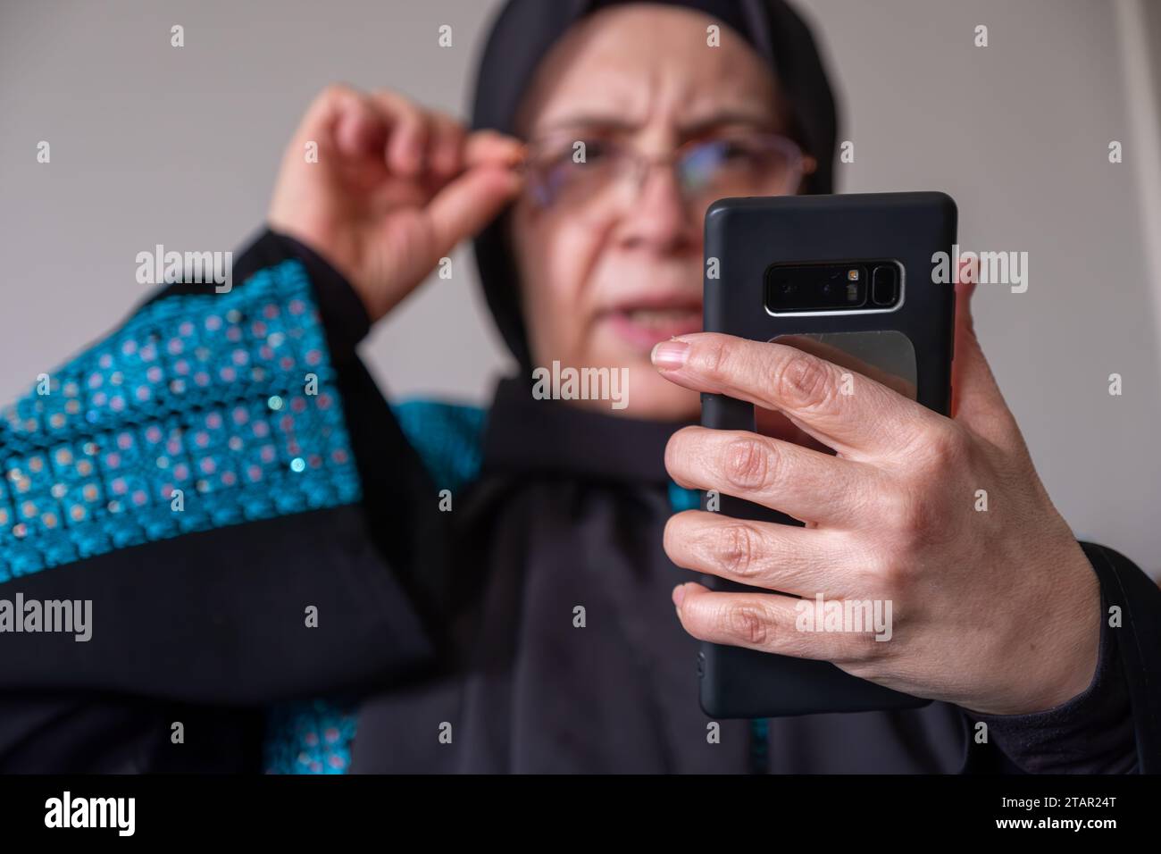 Female wearing palestinian traditional clothes indoor making phone call on couch  with her relatives in palestine Stock Photo