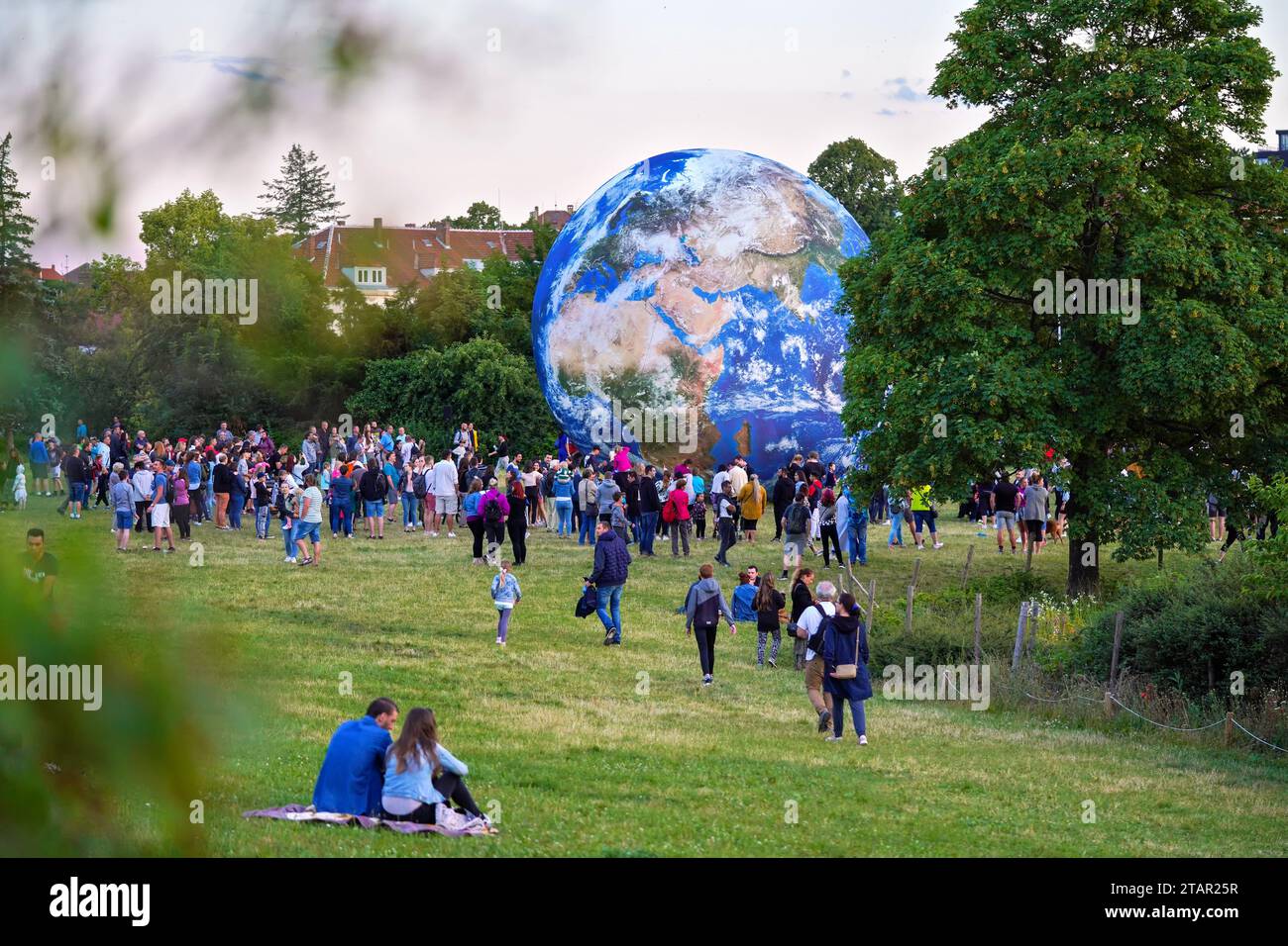 Brno, Czechia - July 12, 2020: People walking in front of inflatable Earth model placed on green grass meadow near planetarium park Stock Photo