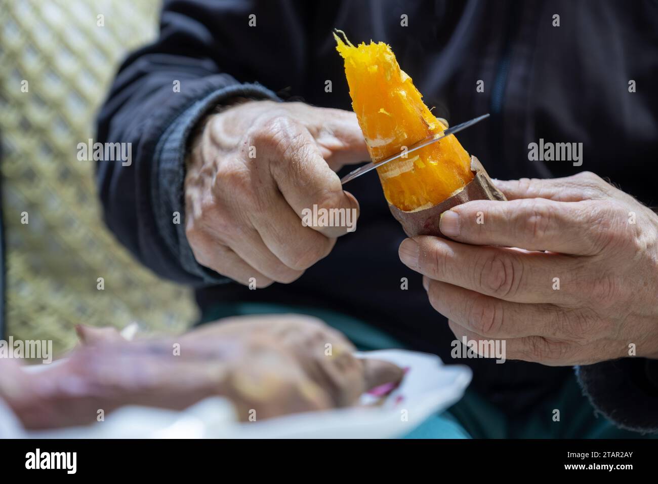 Old man eating sweet potato Stock Photo