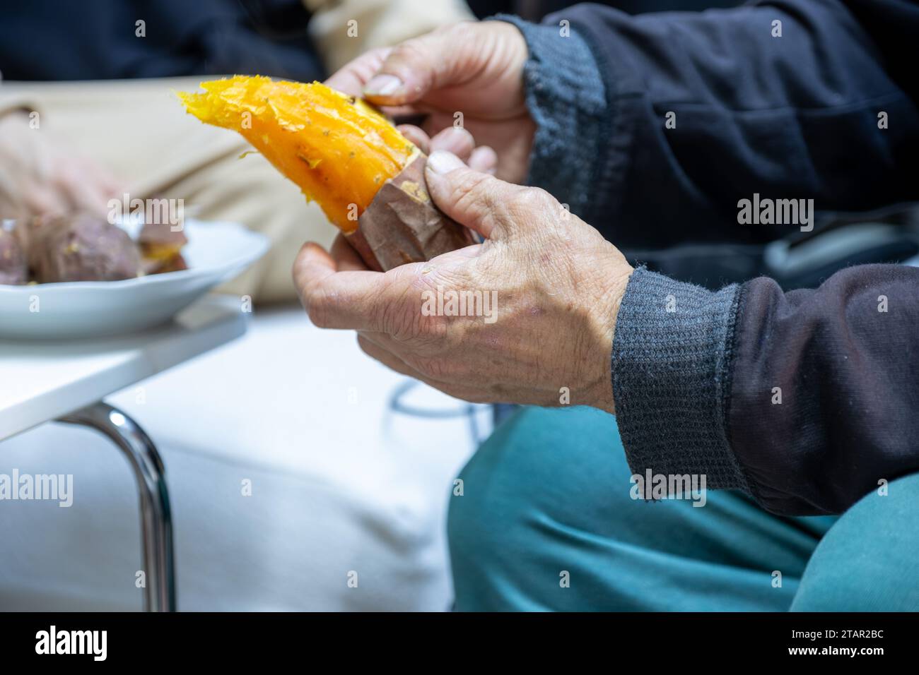Old man eating sweet potato Stock Photo