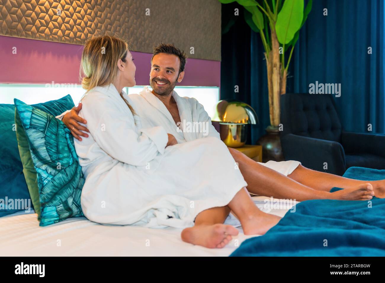 Romantic moment of a couple dressing gown in a hotel room Stock Photo