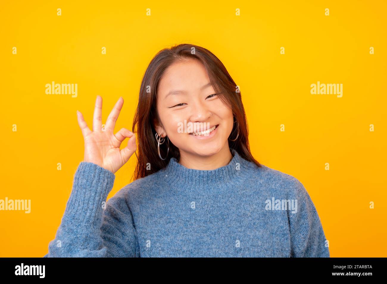 Asian woman acting cool and wonderful looking at camera on a yellow background Stock Photo