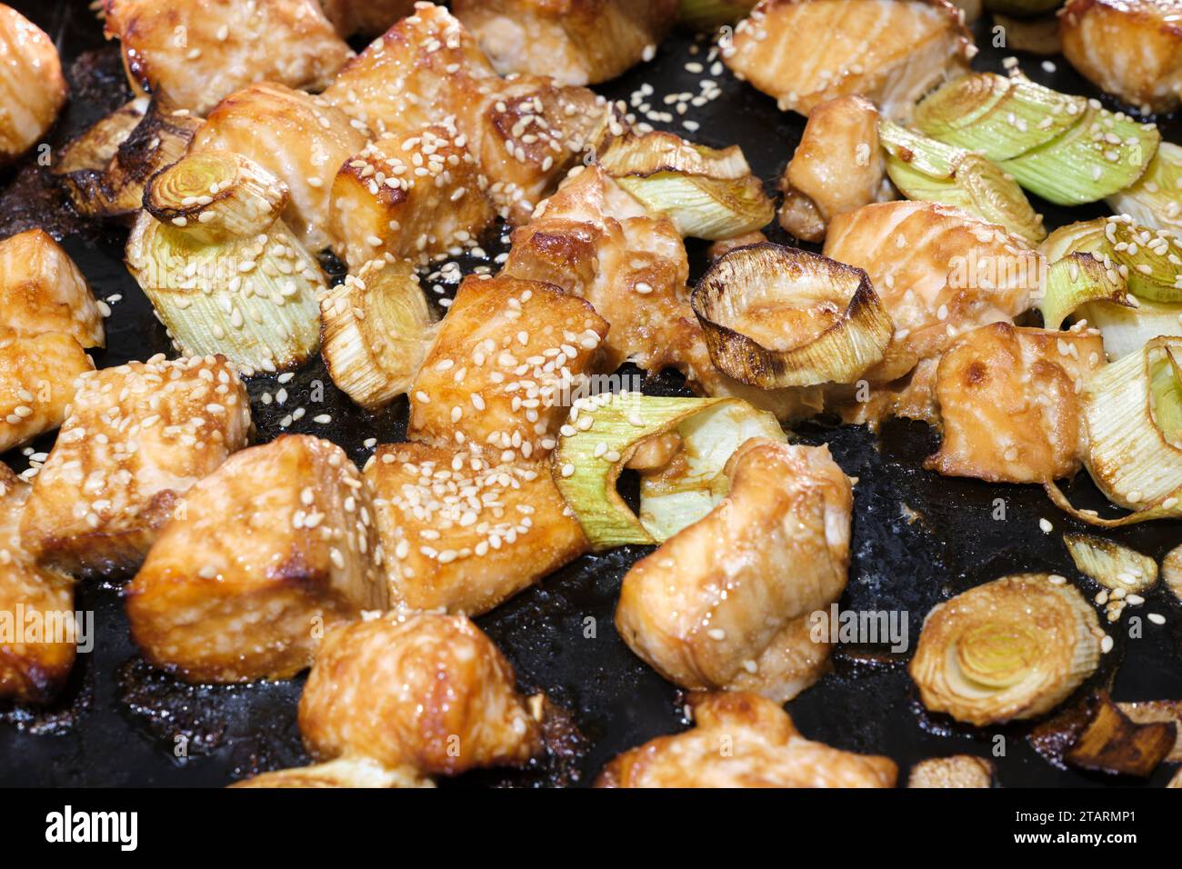 Cubes of teriyaki salmon covered in sesame seeds on oven pan coming out of air fryer Stock Photo