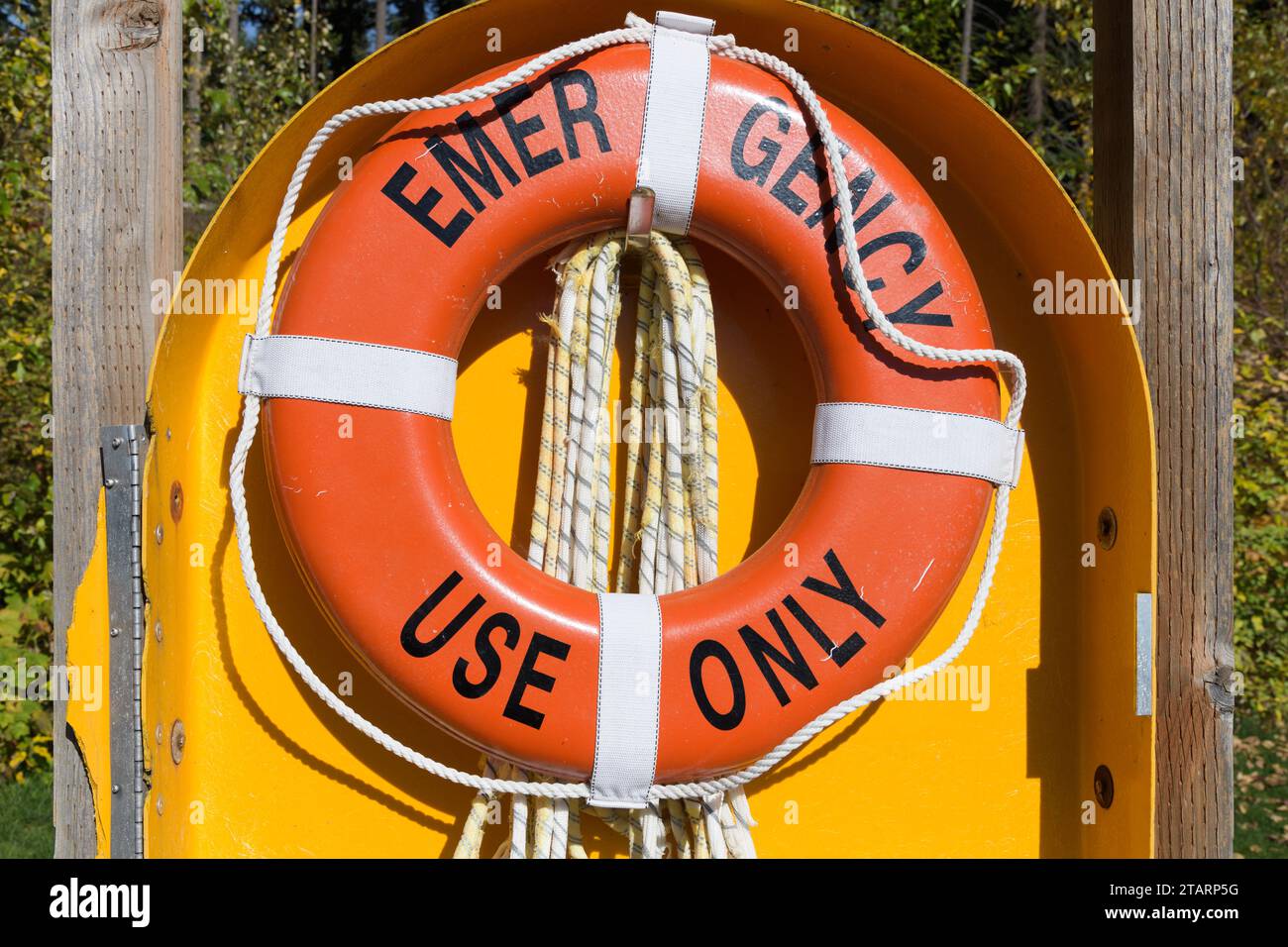 Emergency Use Only orange life ring bouy in yellow surround with rope Stock Photo