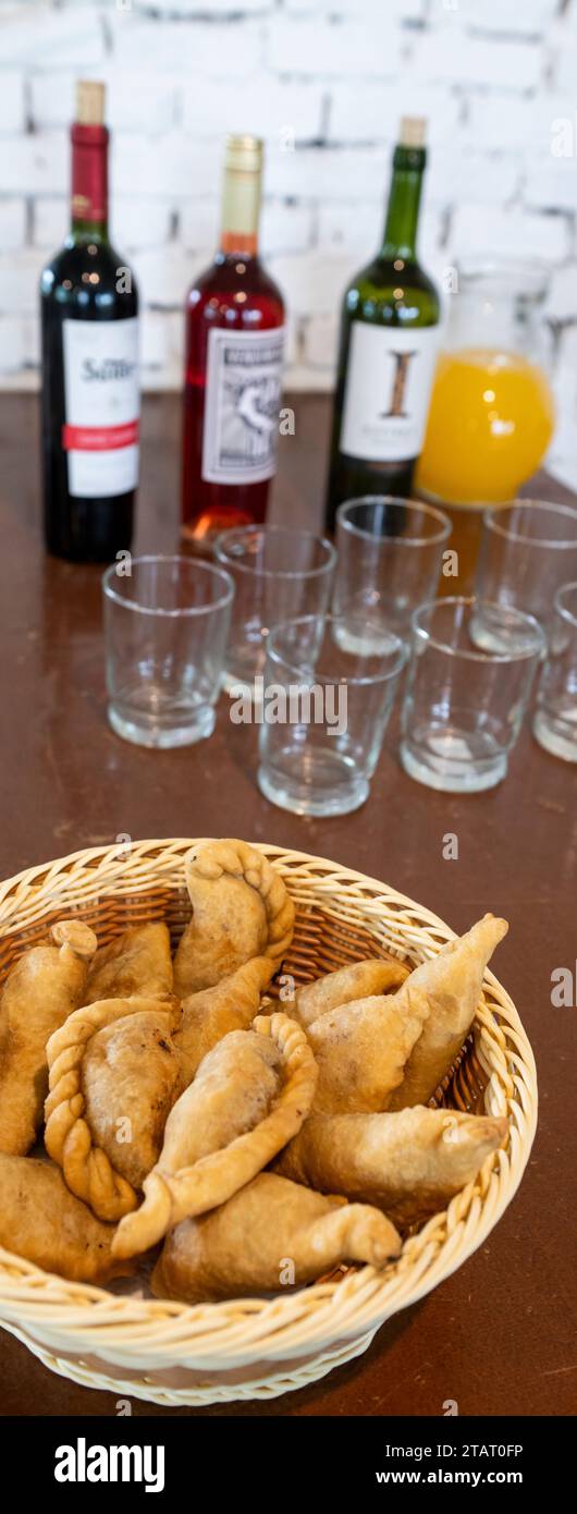 Argentina, Buenos Aires. Traditional savory meat empanadas, wine in the distance. Stock Photo