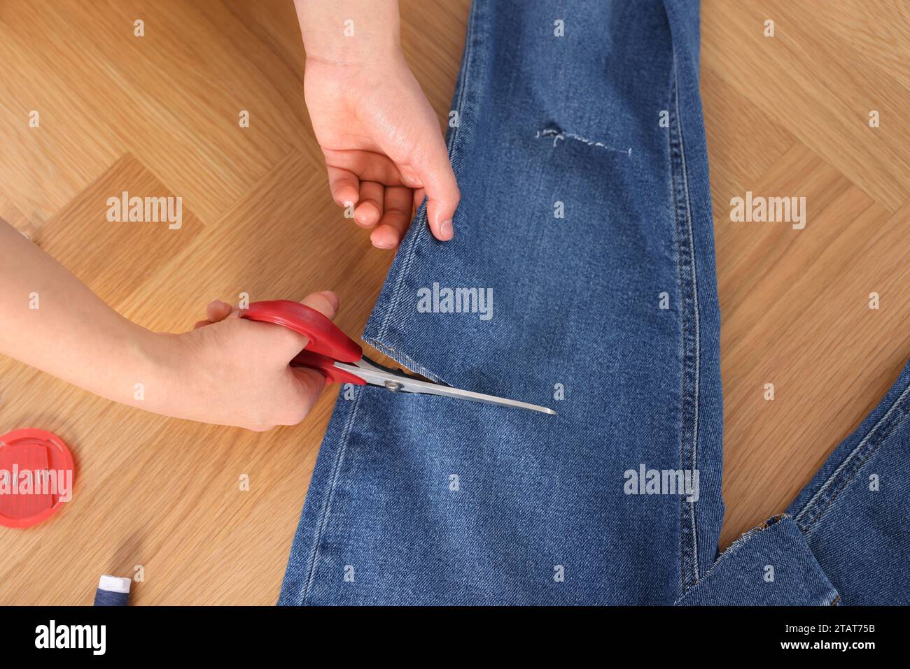 Woman cutting jeans with scissors at wooden table, top view Stock Photo