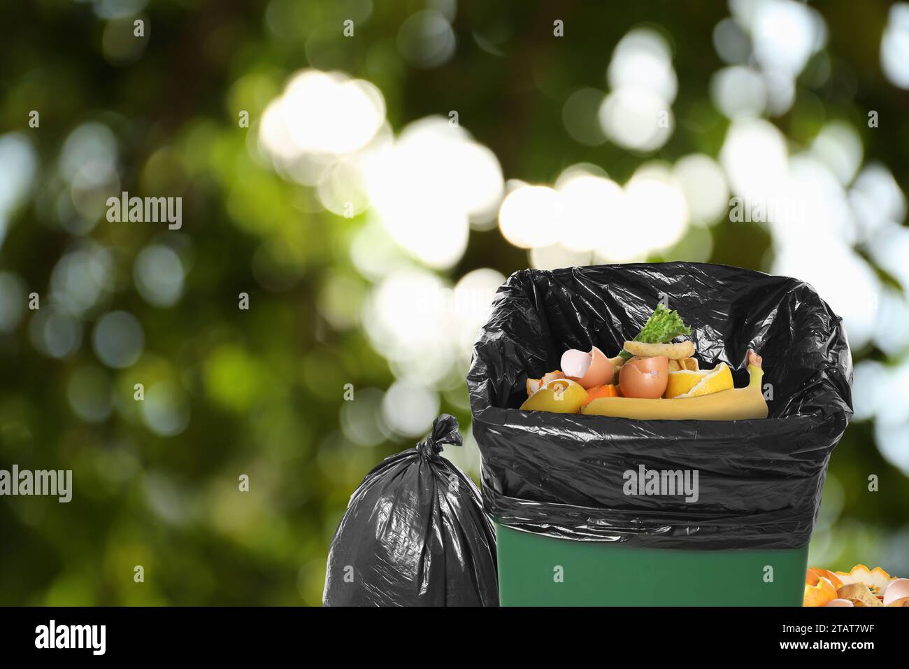 Waste bin and plastic bags full of garbage on blurred background, space ...