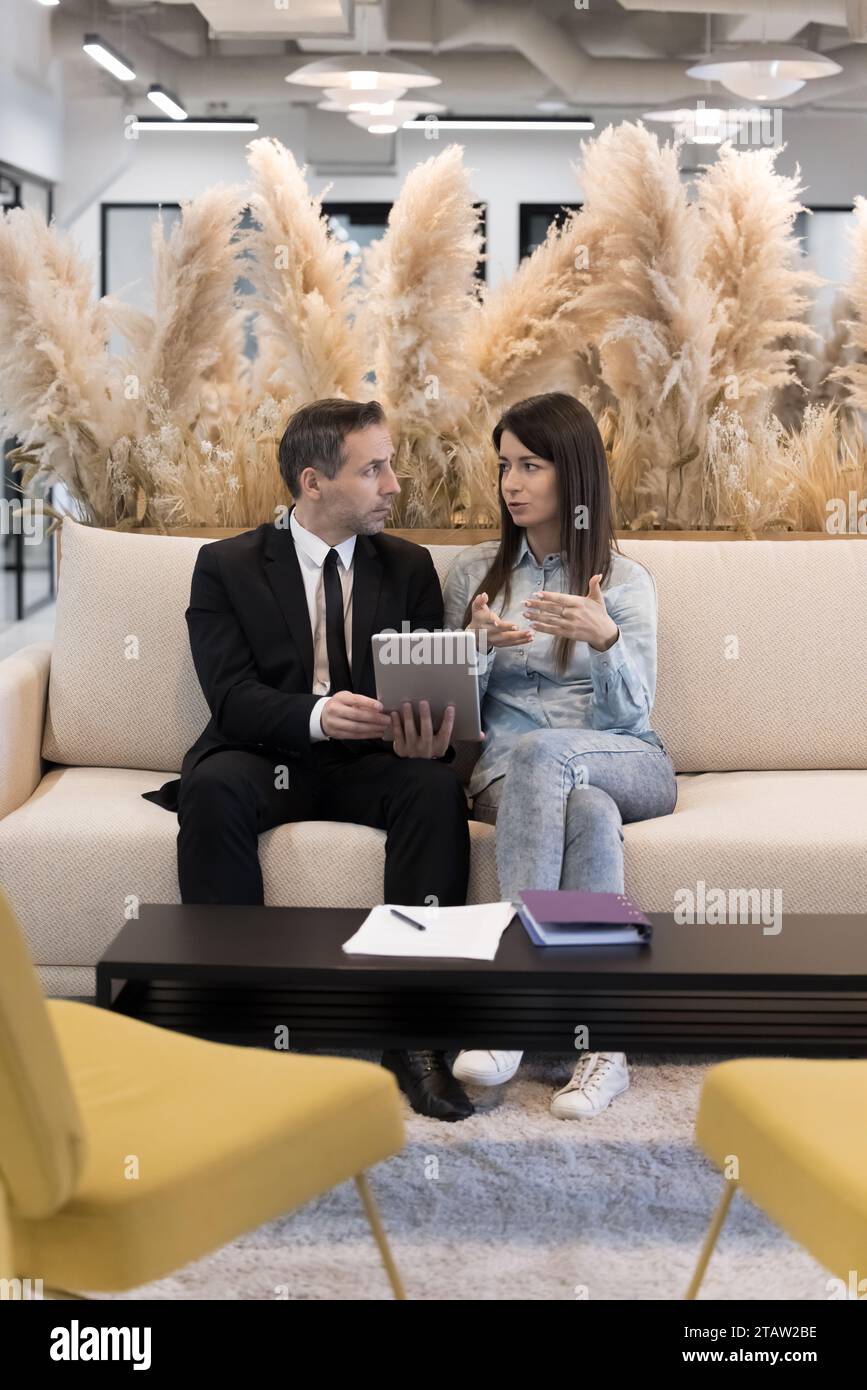 Mature and young colleagues using modern application on digital tablet Stock Photo