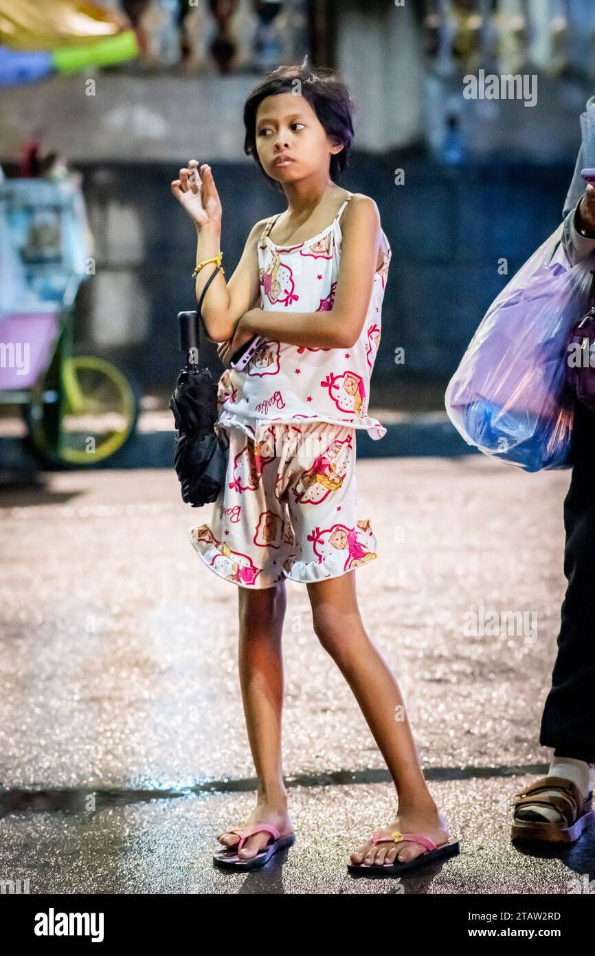 A pretty young filipino girl waits for her family outside Santo Nino de Tondo Church in Manila, The Philippines. Stock Photo