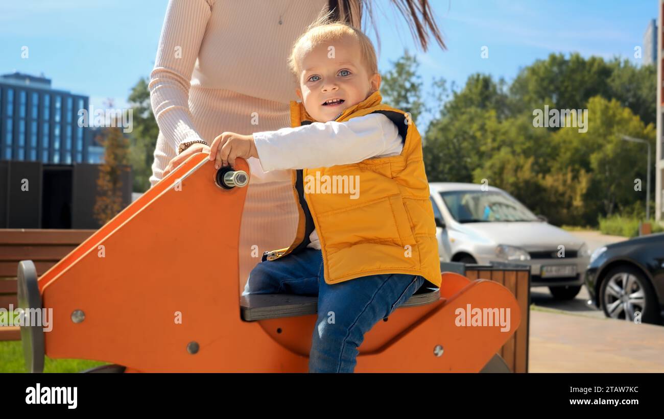 Cute baby boy riding on the spring rider at playground. Happy parenting ...