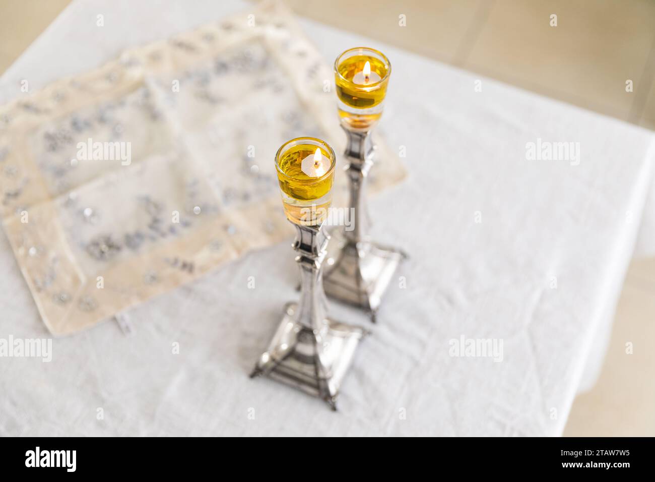 A pair of Shabbat candles are lit with oil on silver candlesticks on the Shabbat table Stock