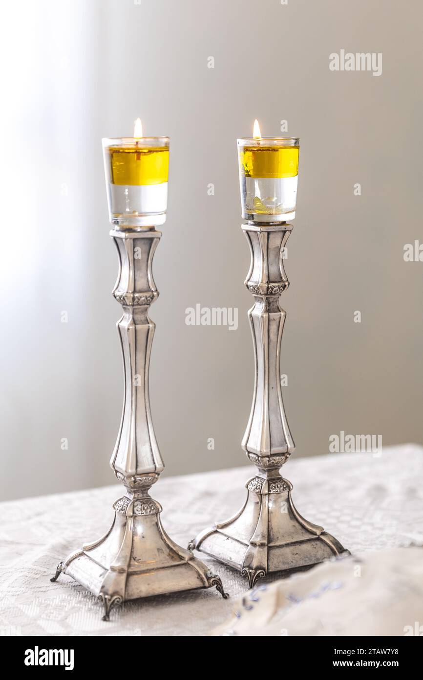 A pair of Shabbat candles are lit with oil on silver candlesticks on the Shabbat table Stock