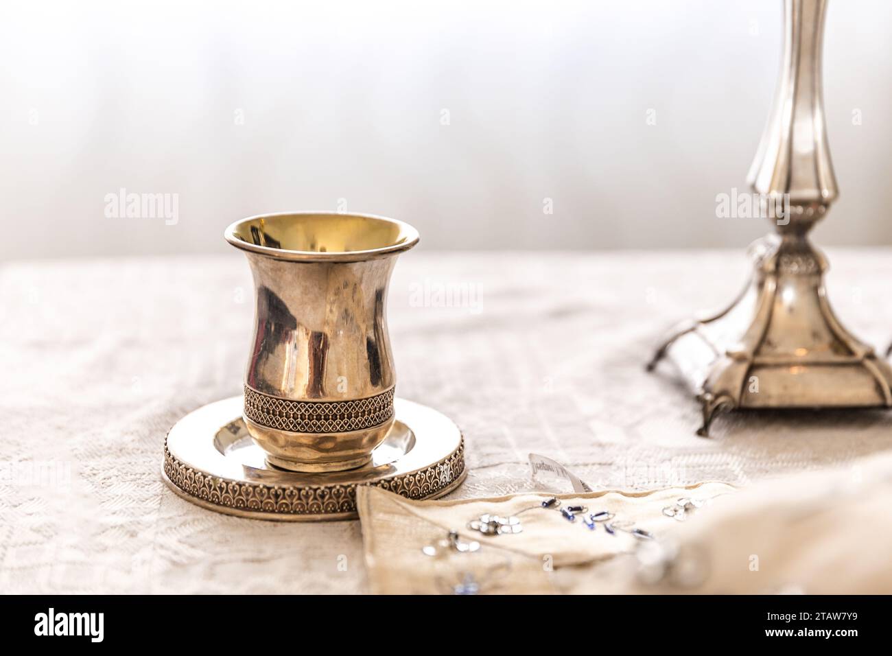Traditional, decorative Jewish kiddush cup. Silver cup with saucer filled to the brim with purple wine isolated on a white background Stock Photo