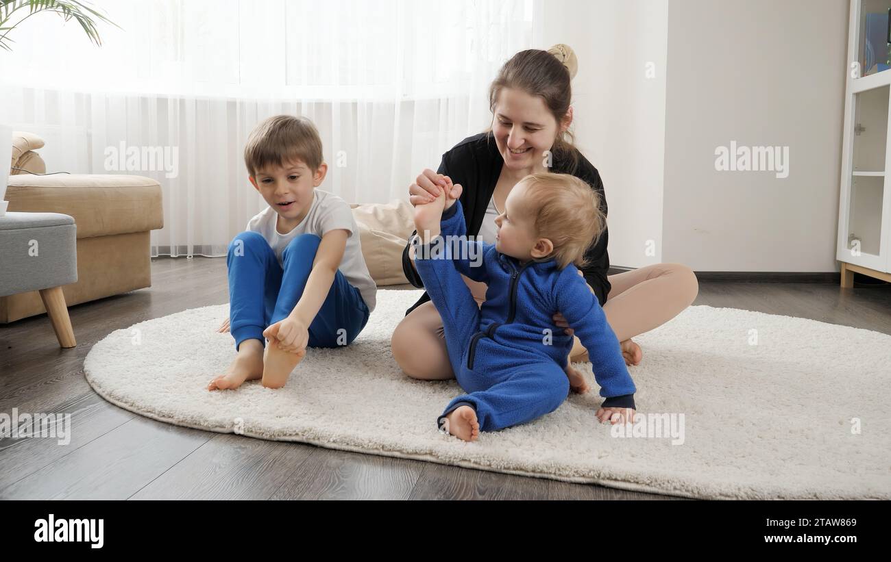 Happy smiling family with two little boys practising yoga and fitness ...