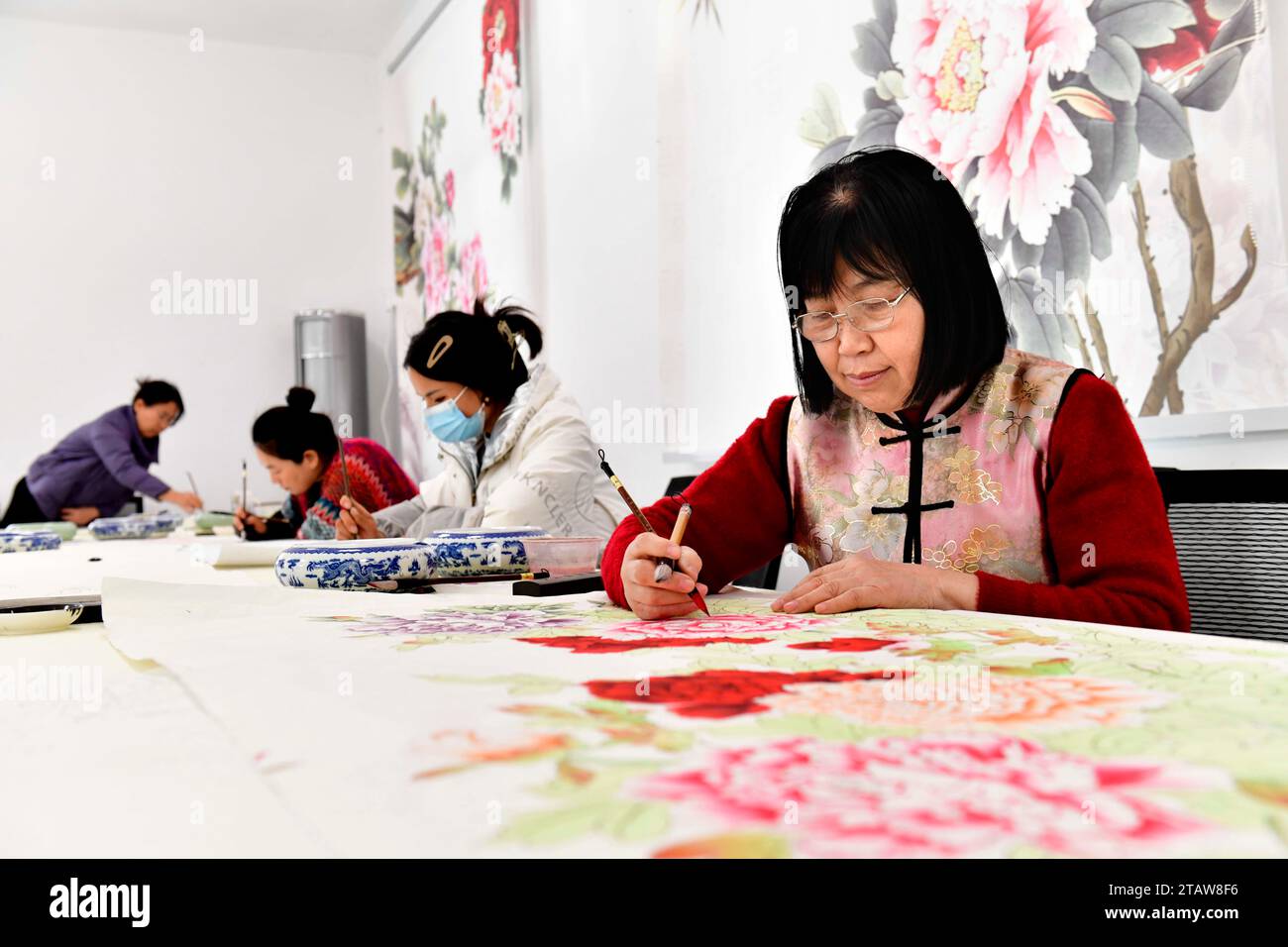 Juye, Heze City of east China's Shandong Province. 2nd Dec, 2023. Farmers paint peony-themed realistic paintings at a studio in Juye County, Heze City of east China's Shandong Province, Dec. 2, 2023. Juye County is located in Heze, a city known for the cultivation of peonies. As a provincial intangible cultural heritage, peony-themed realistic painting has not only subsidized locals' incomes but also become a respected pastime within the community. There are over 20,000 people engaged in painting industry at present. Credit: Guo Xulei/Xinhua/Alamy Live News Stock Photo