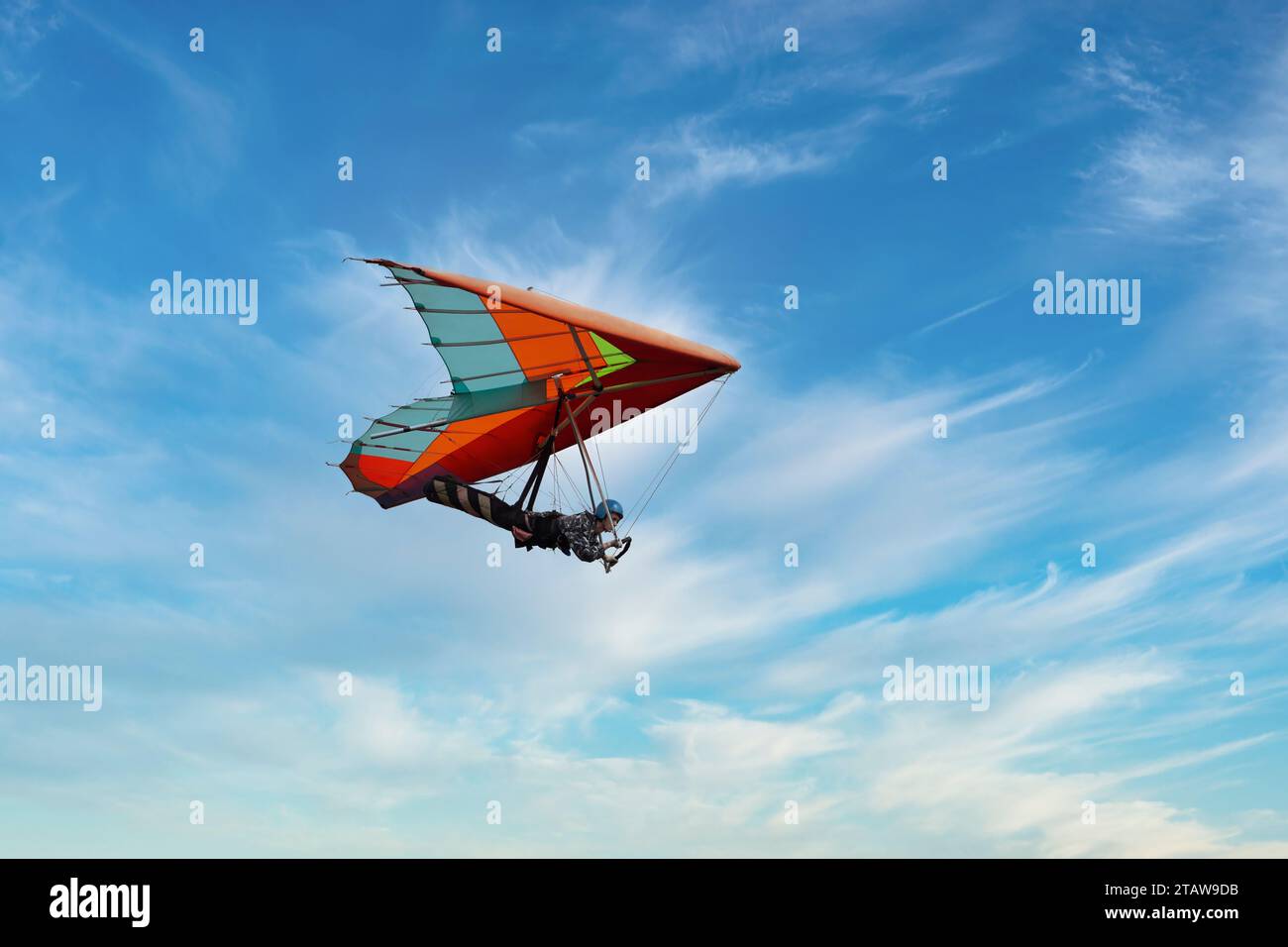 Red hang glider soaring in the blue sky. Colorful kite wing Stock Photo
