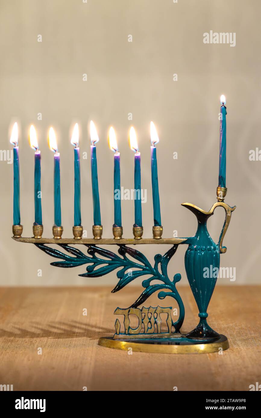 Beautiful Menorah (Chanukkiah) with 8 lit burning candles for Jewish Hanukkah holiday on table at home. Celebrating Chanukah festival of lights. Stock Photo