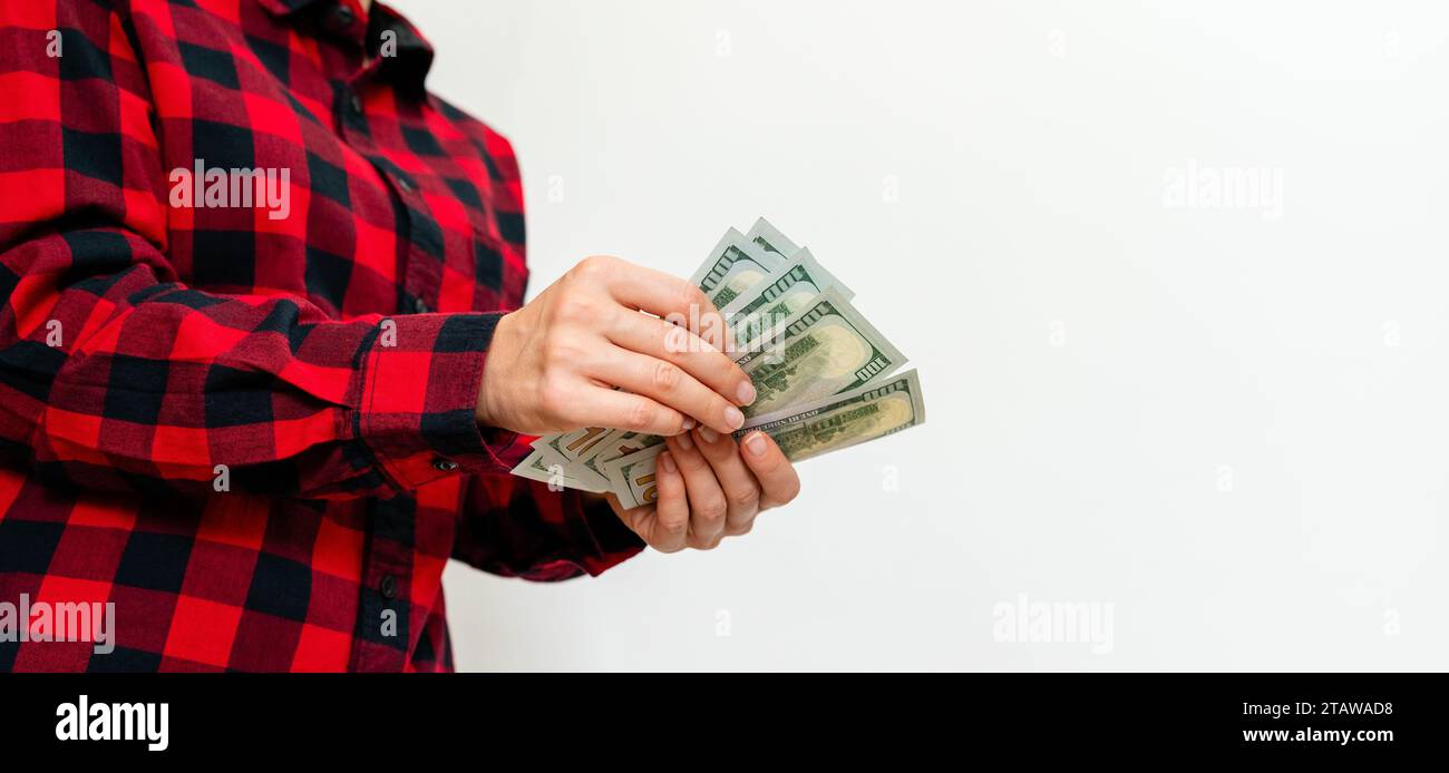 Female person in red casual shirt counting dollars bills in her hands, united states currency. Stock Photo