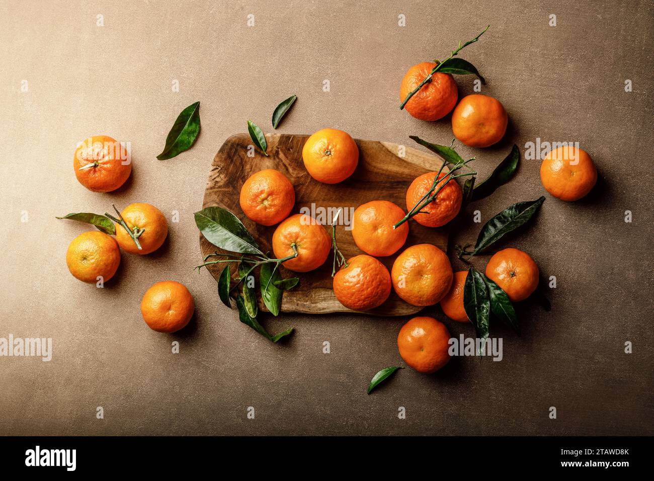 Mandarin oranges, clementines or tangerines with leaves on a dark background, top view Stock Photo