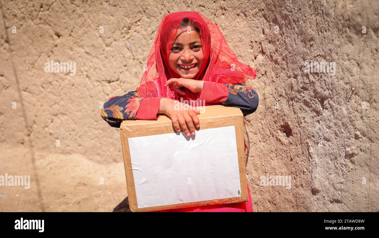 Needy Afghan girl receiving donations | Children expressing happiness after receiving aid food packs | Needy kid holding aid pack Stock Photo