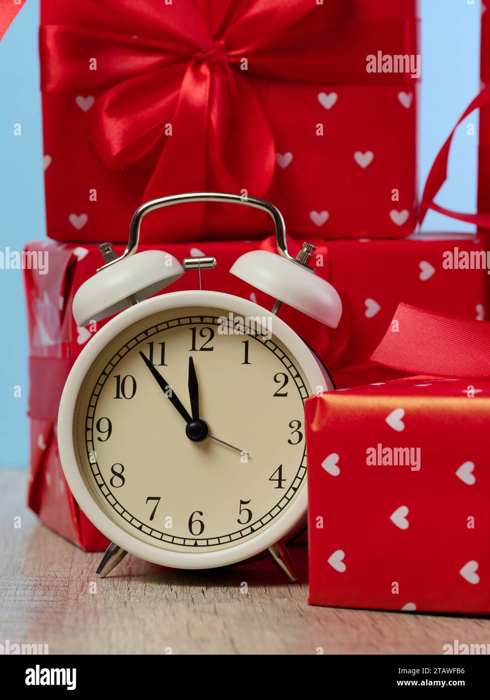 Alarm clock and stack of red gift boxes on blue background Stock Photo