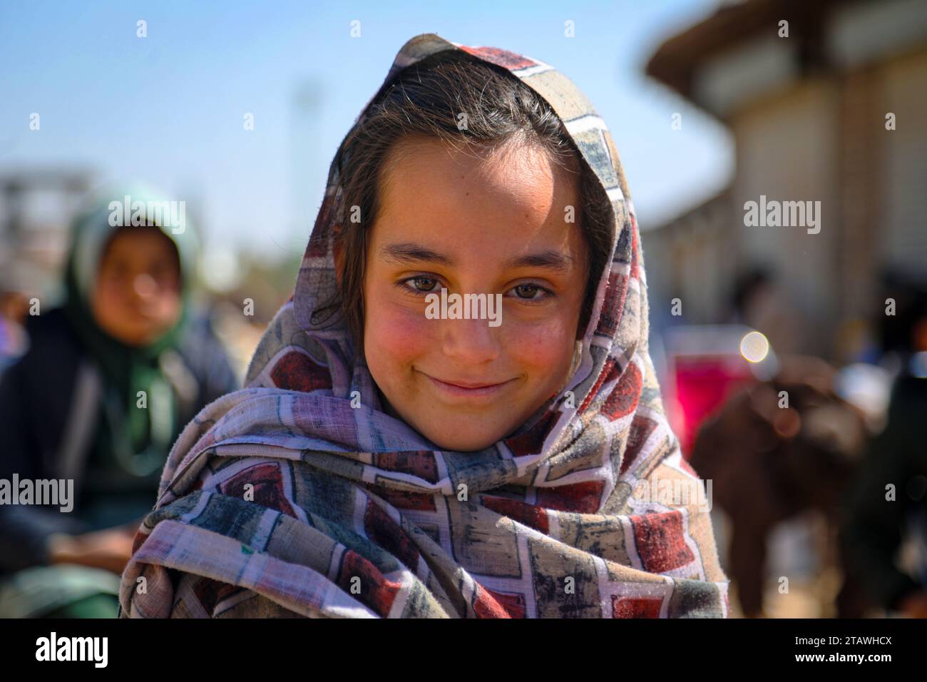 Happy Afghan young girl with a traditional outfit, smiling, looking at the camera. Stock Photo