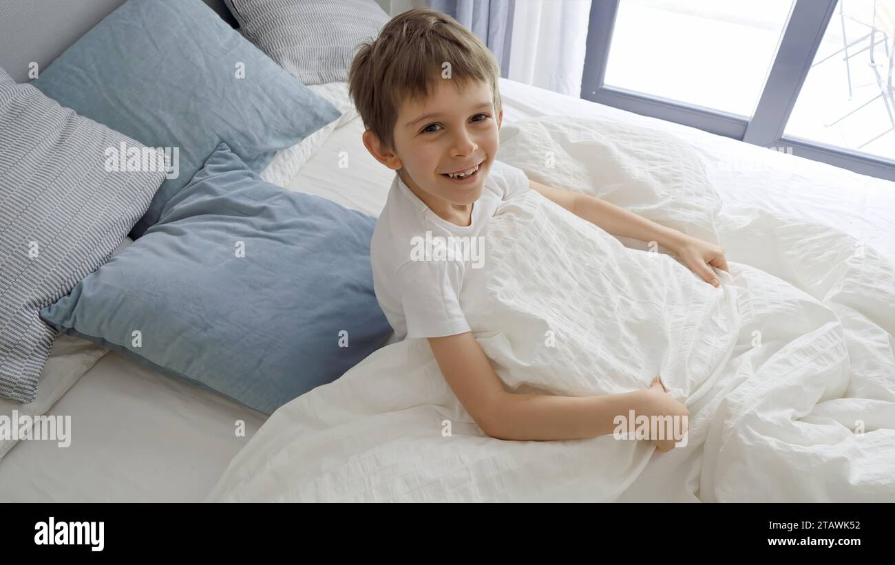 Little boy jumping out from under his blanket with a smile on his face