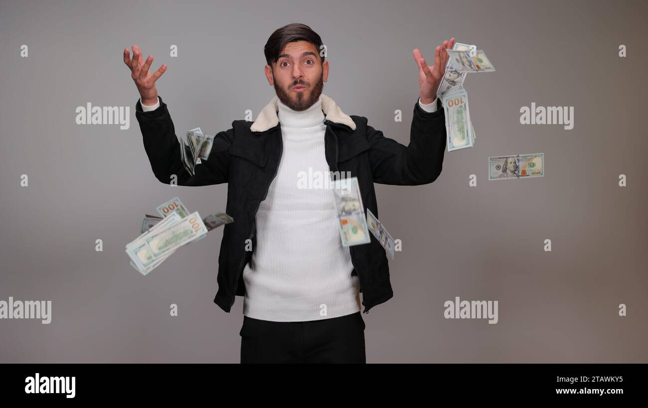 Rich man threw all the money up and they fly around. Indoor, studio shot, isolated on gray background. Stock Photo