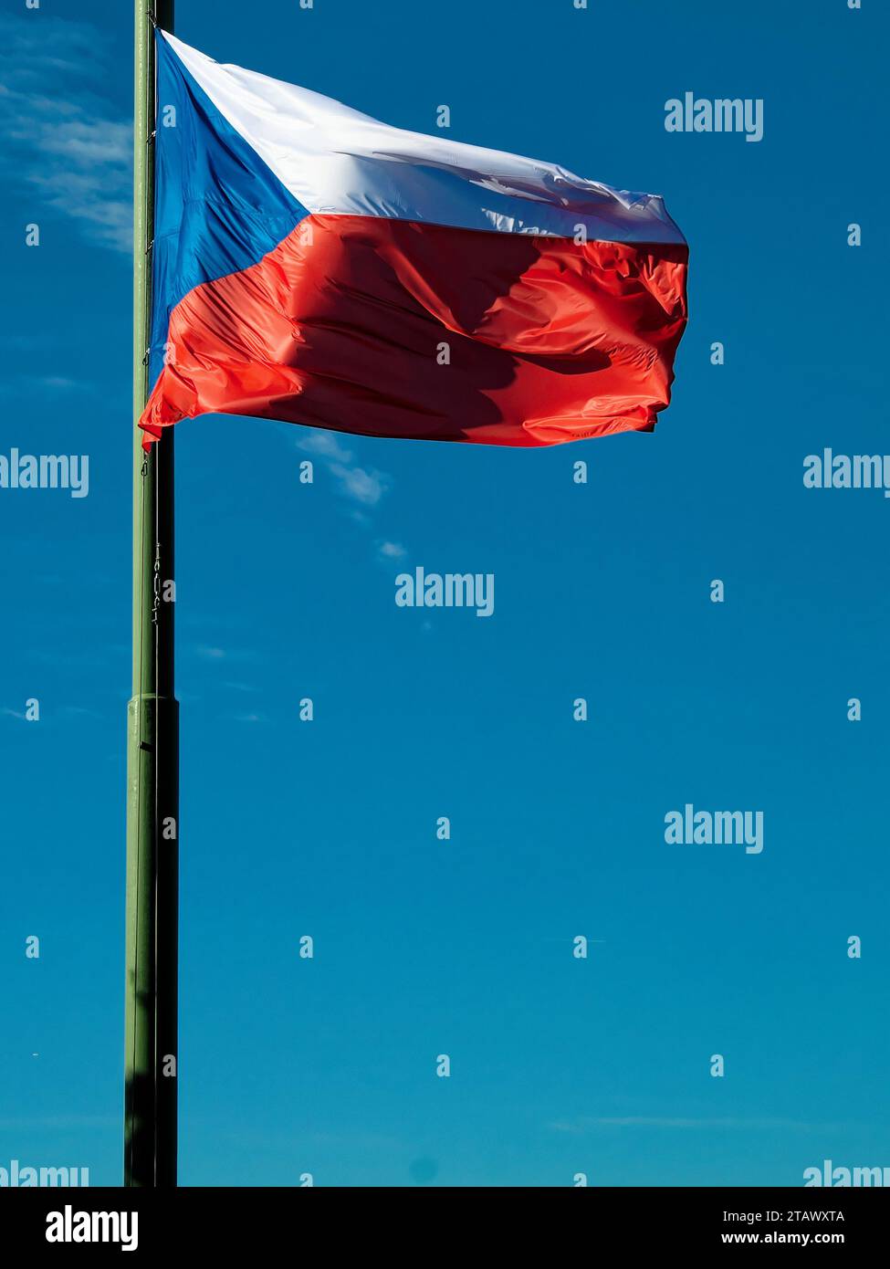 The Czech Republic flag is waving in the wind on a flagpole with a clear blue sky in the background. Stock Photo