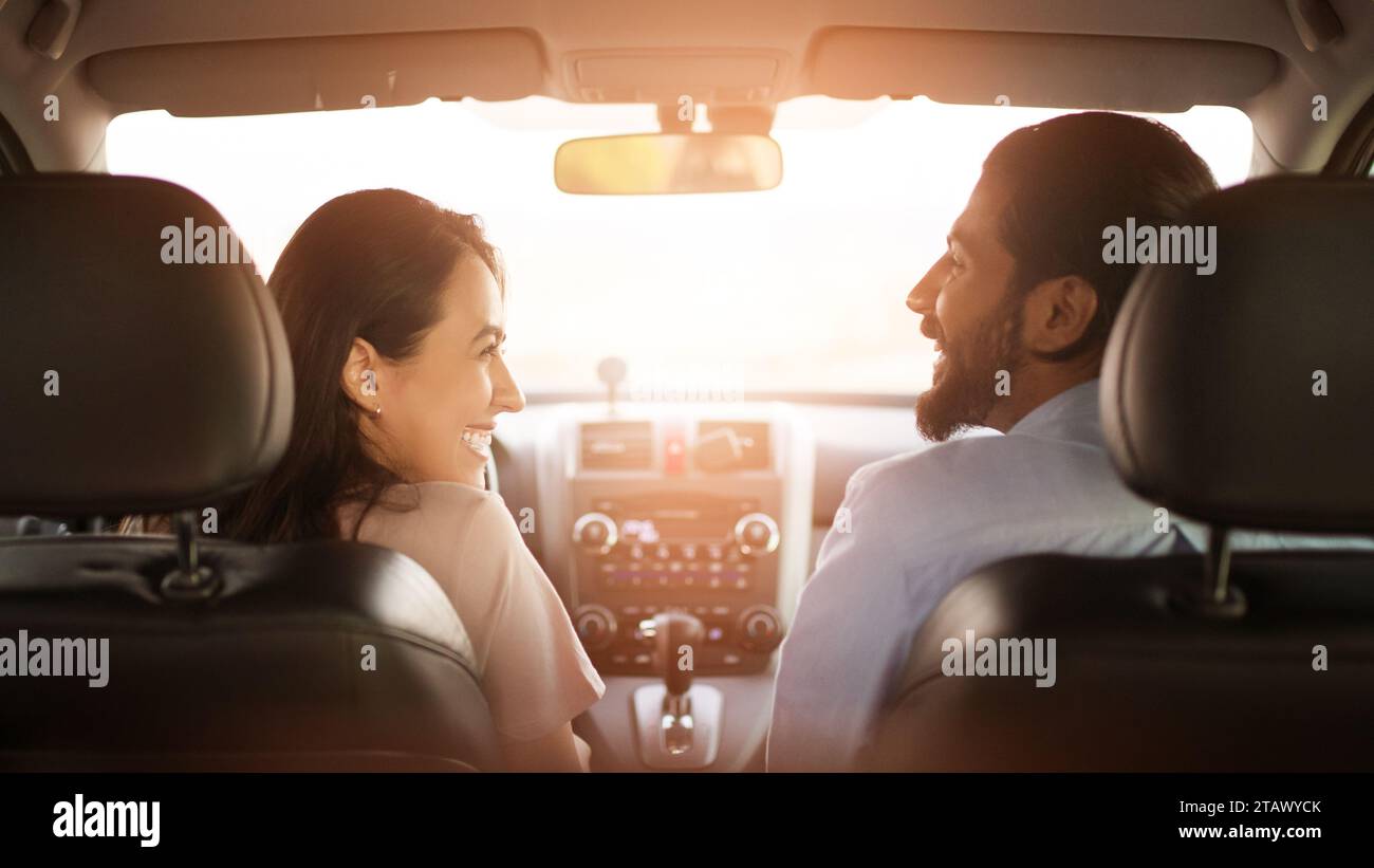 Arab couple conversing in car, sunlight behind Stock Photo