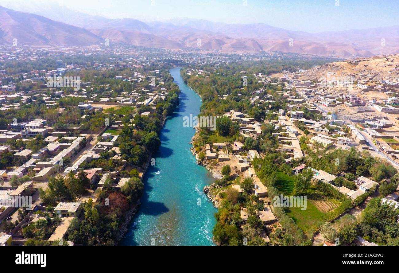 A river flowing through a green village and mountains in Afghanistan ...