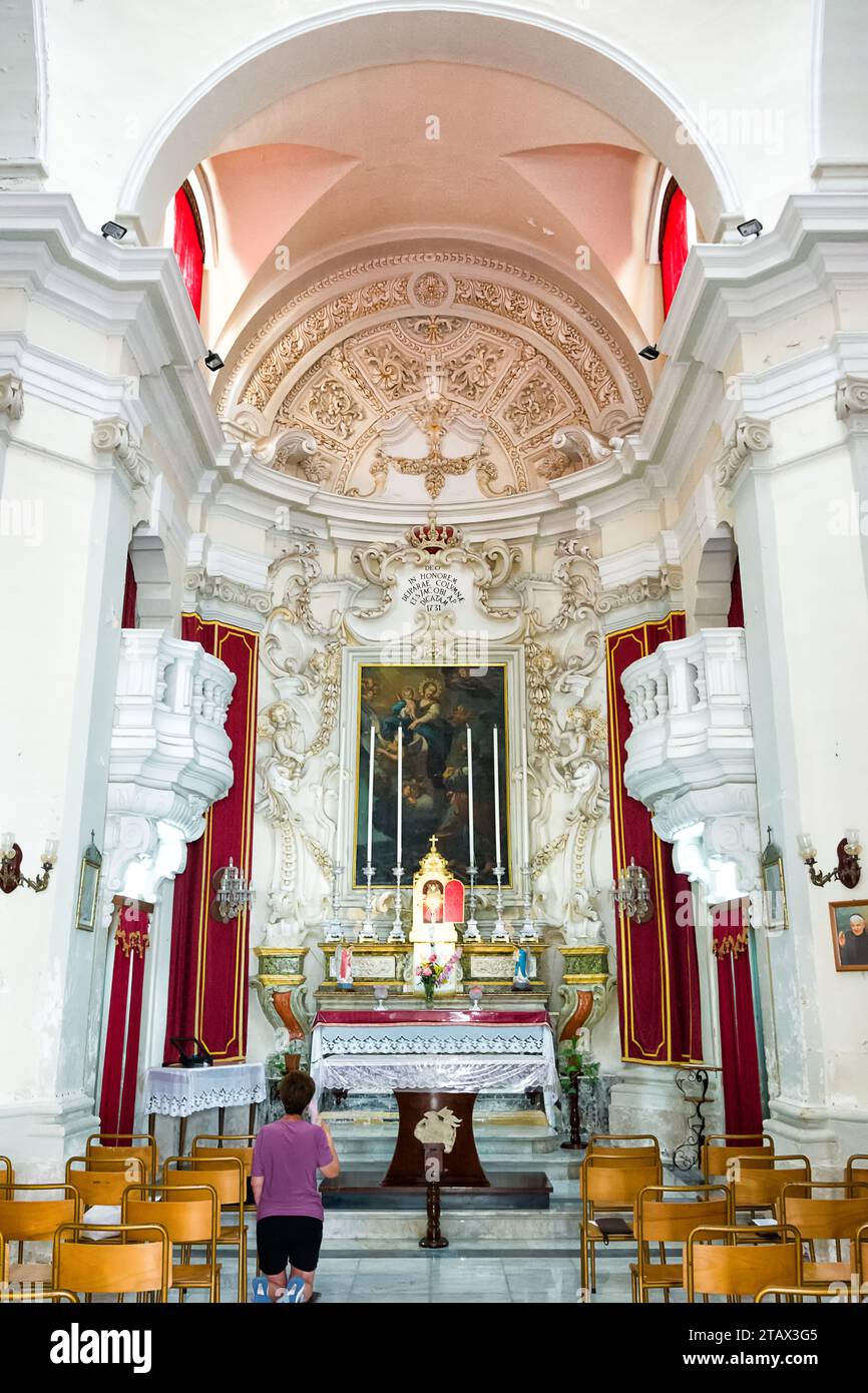 Zurrieq, Malta - 18 June 2023: Interior of St. Gakbu Chapel with a worshiper praying on her knees Stock Photo