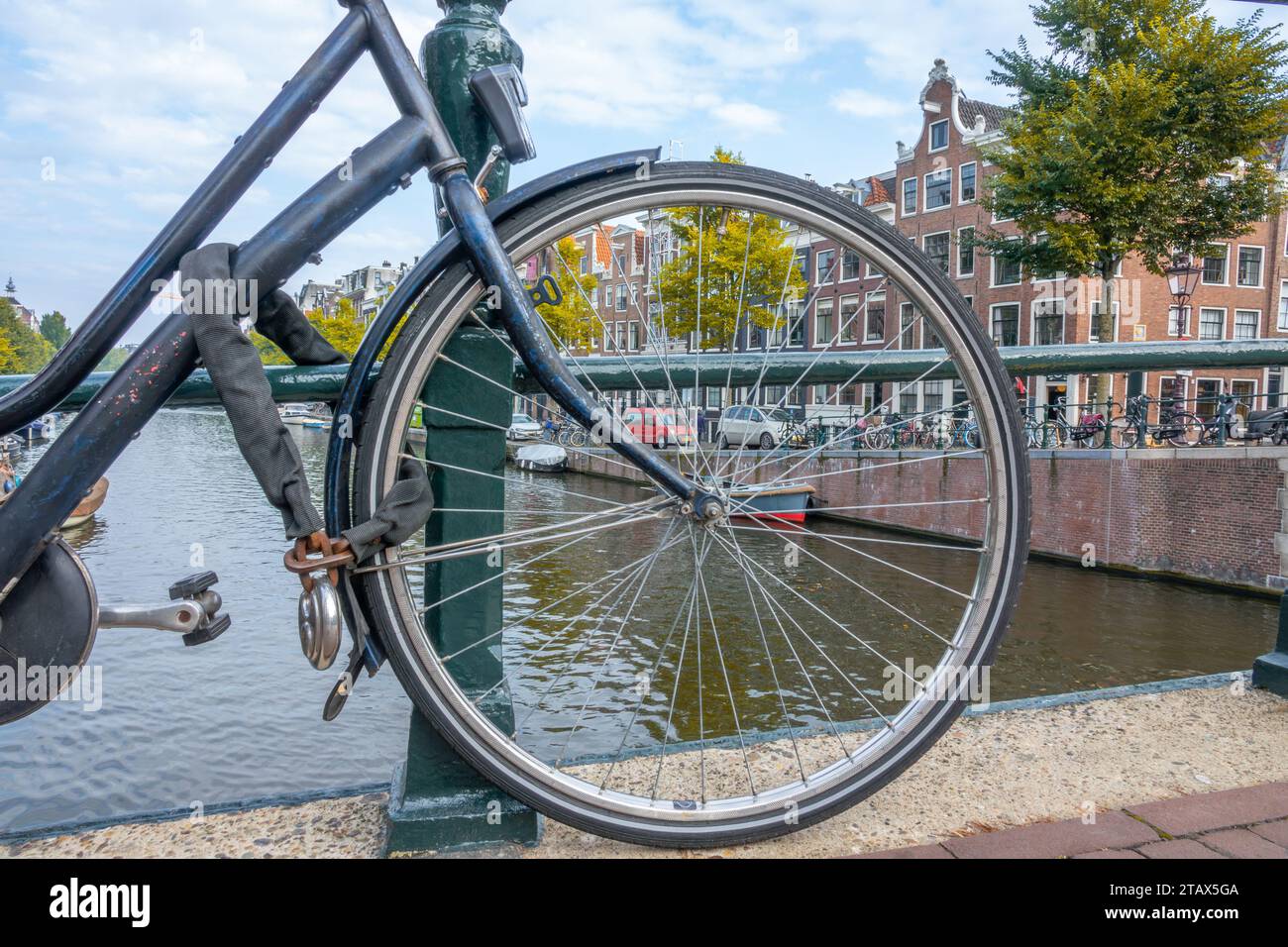 Netherlands. Autumn day in Amsterdam. The wheel of a bicycle parked on the bridge and the canal embankment Stock Photo