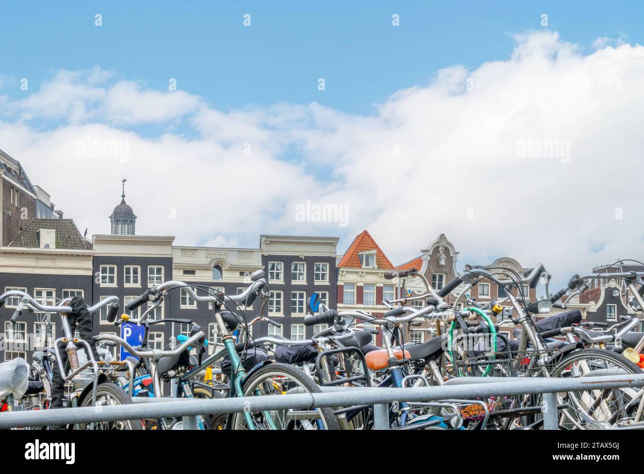 Netherlands. Daytime Amsterdam and light clouds in the blue sky. Bicycles in the parking lot and facades of typical Dutch buildings Stock Photo