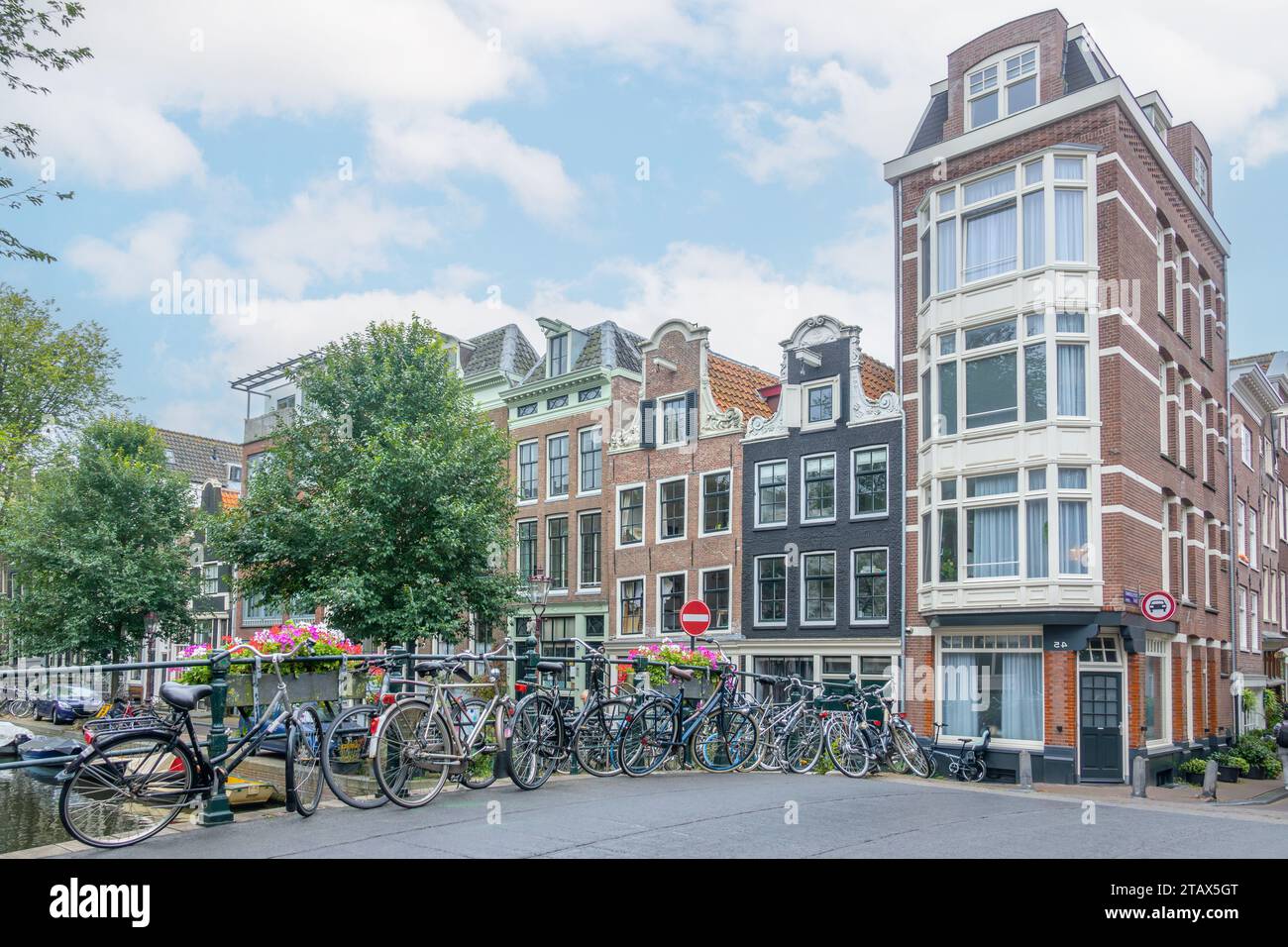 Netherlands. Summer day in Amsterdam. Light clouds in the blue sky. Several bicycles are parked near the railing of a bridge over a canal Stock Photo