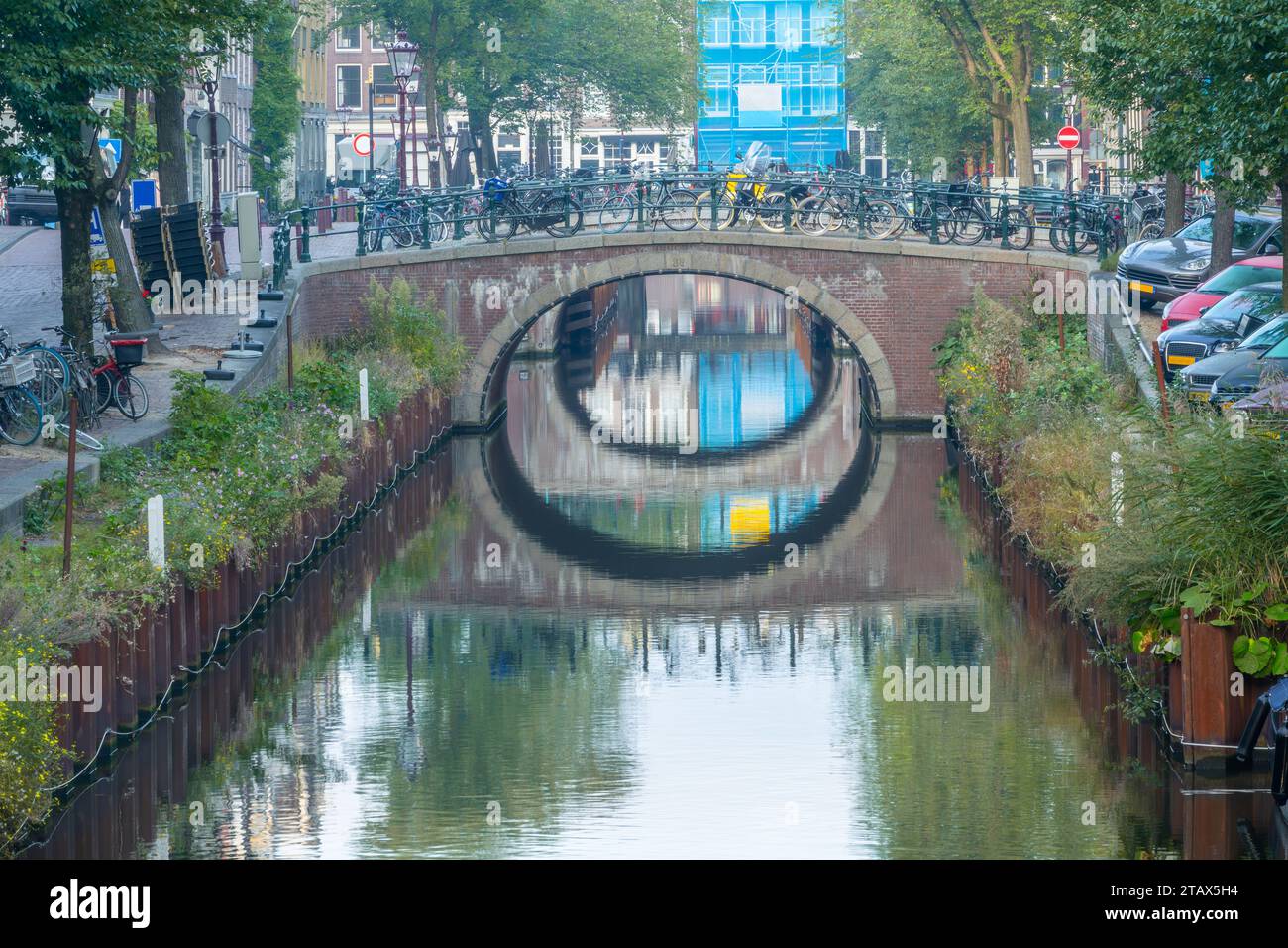 Netherlands. Summer day on a canal in the center of Amsterdam. Lots of bicycles and cars on the bridge and embankments Stock Photo