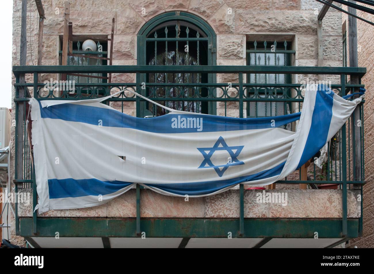 A torn and weathered flag of Israel tied to a green balcony on Independence Day in Jerusalem, the capital of Israel. Stock Photo