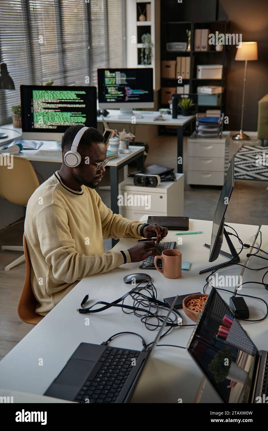 Serious software developer working on laptop at his desk reviewing ...