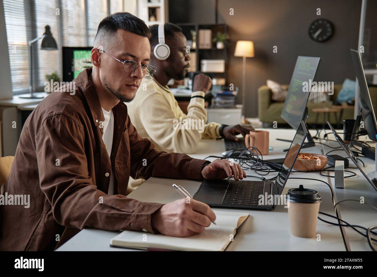 Dev team lead reviewing code and taking notes in planner Stock Photo ...
