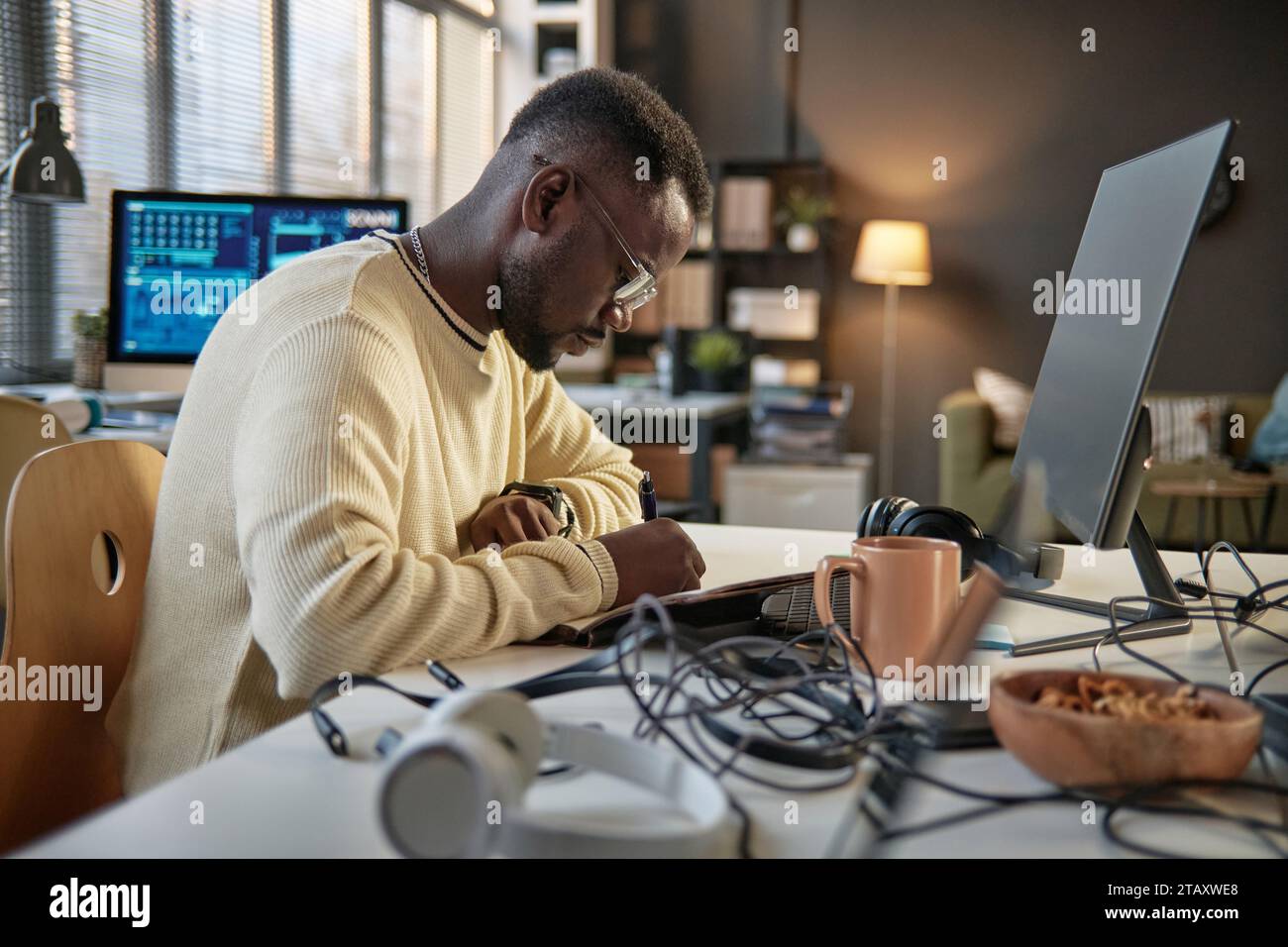 Pensive programmer writing down his ideas when working on project Stock Photo