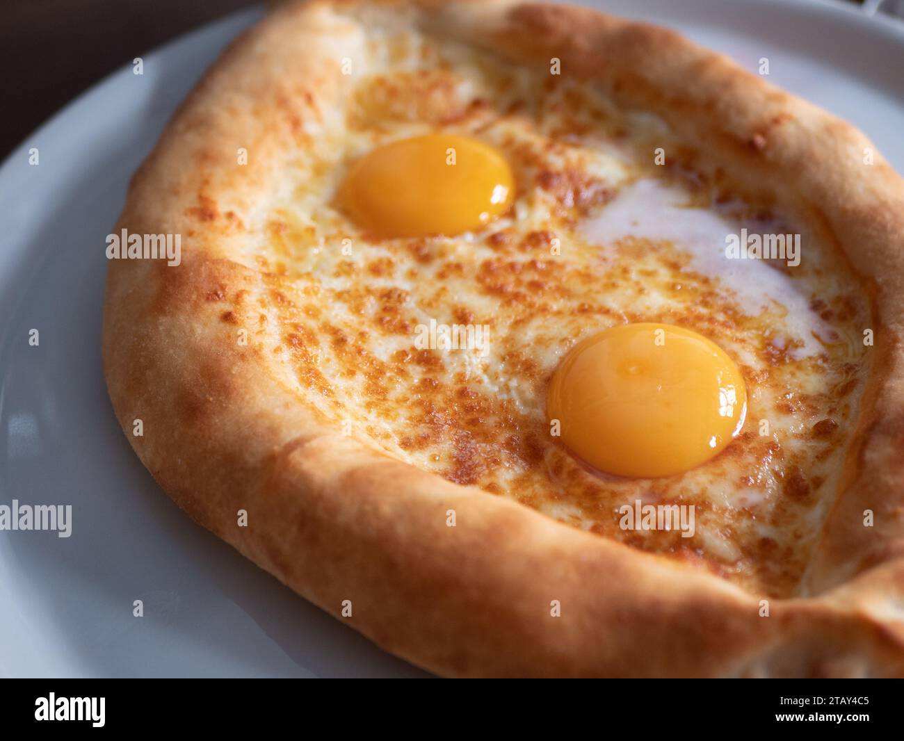 Boat-shaped Adjarian khachapuri on the plate, selective focus. Georgian traditional cuisine Stock Photo