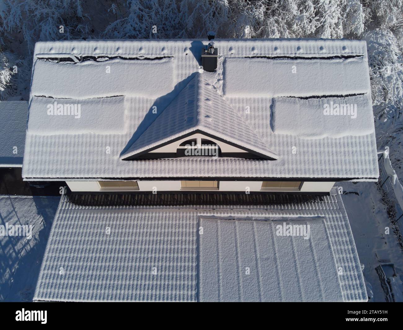 Snow blankets solar panels on a house roof in winter. Despite the