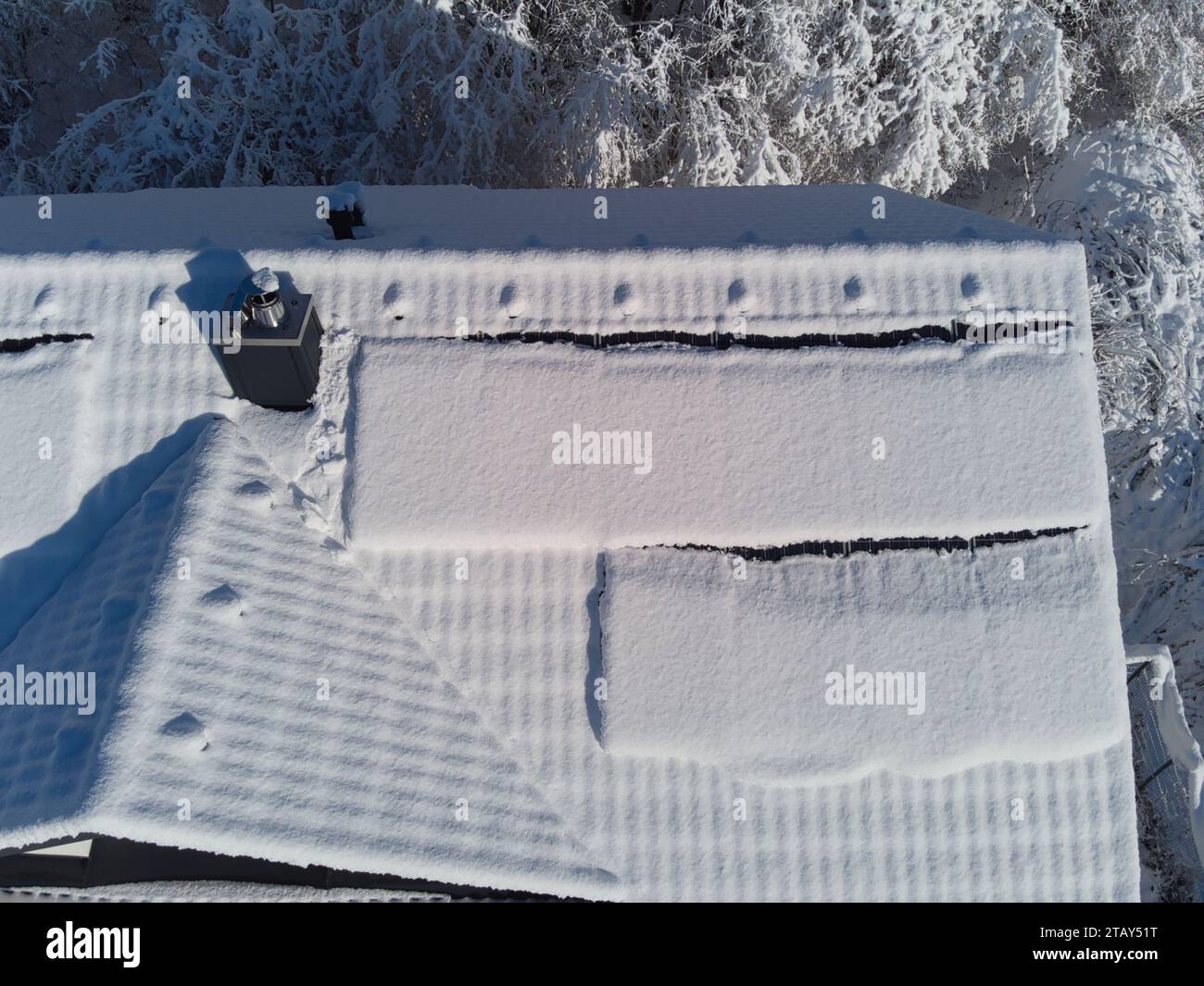 Snow blankets solar panels on a house roof in winter. Despite the