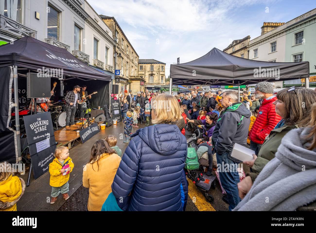 Rock band playing music to large audience on busking stage at Frome