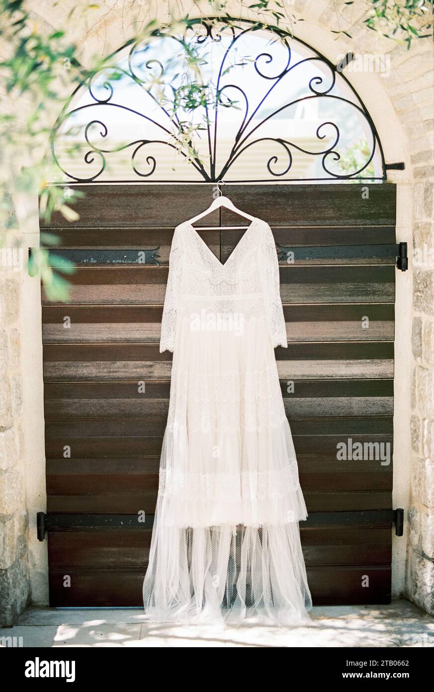 White wedding dress hangs on a hanger on the arched wrought-iron ...