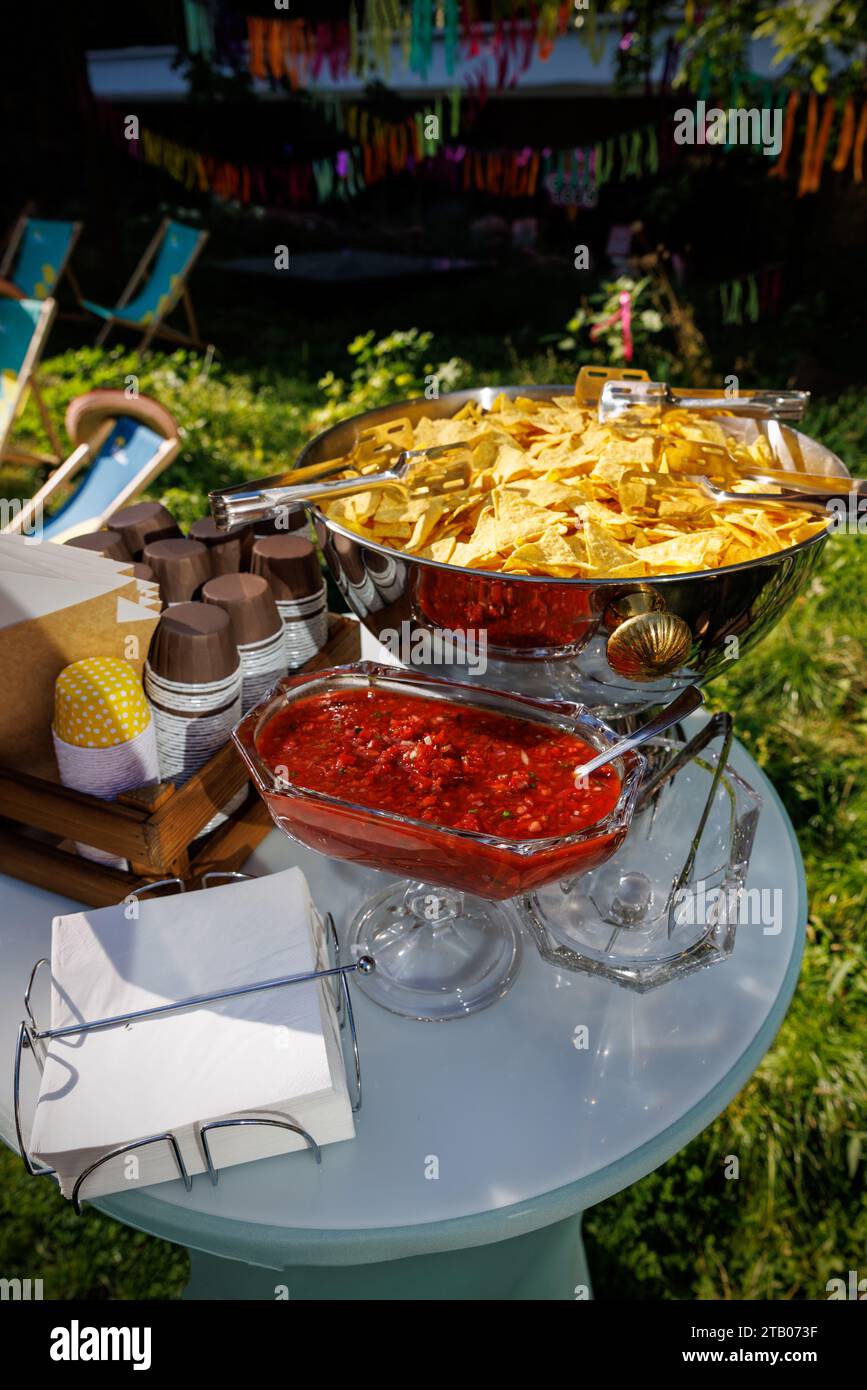 A festive table set for a summer garden Mexican party with colorful decorations, snacks, and drinks. Stock Photo
