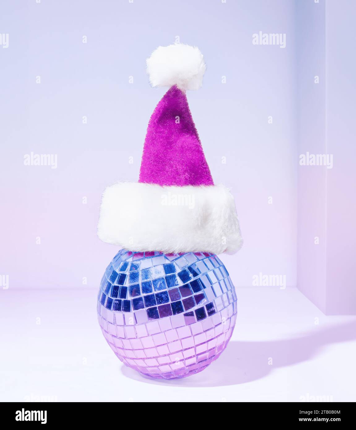 A Mirror Disco Ball Wearing a Purple Santa Claus Hat on A Pastel Purple