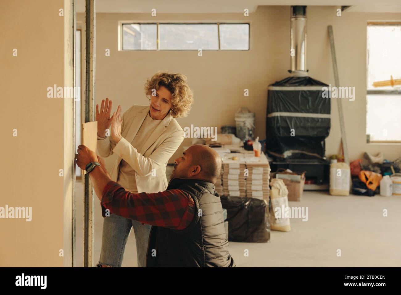 Female architect and a mature male contractor discuss interior renovations in a kitchen. They plan to remodel and upgrade the doors, working together Stock Photo